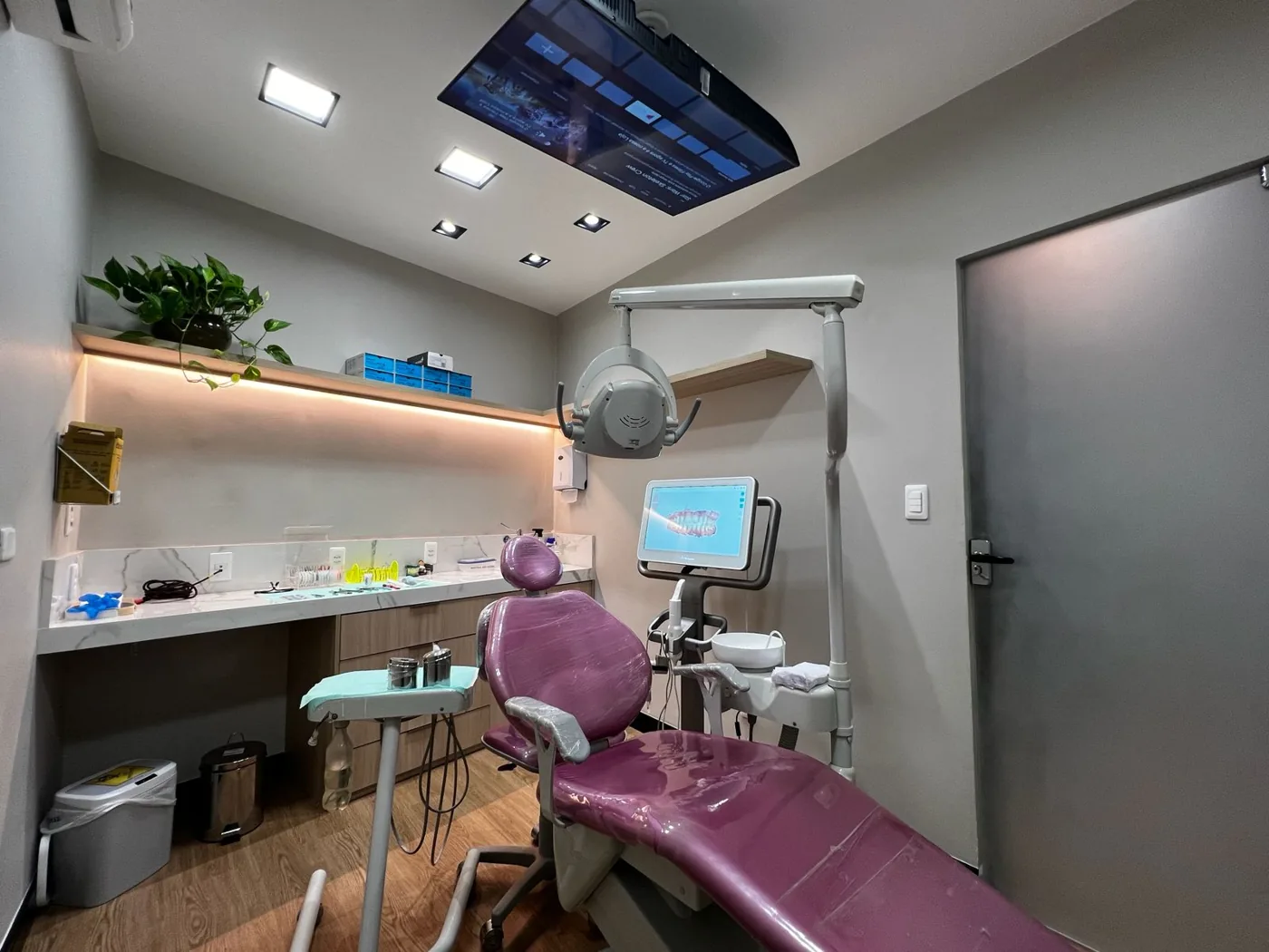 Consultório com cadeira odontológica e TV no teto na Dentista Méier